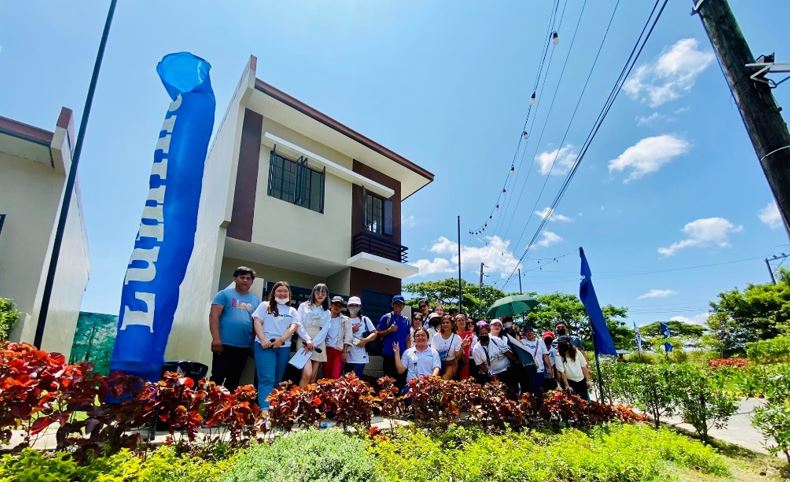 Employees and sellers pose at the front of model home with eco-bin